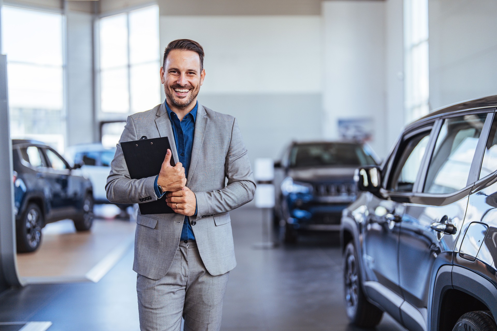 Salesperson at car dealership selling vehicles.